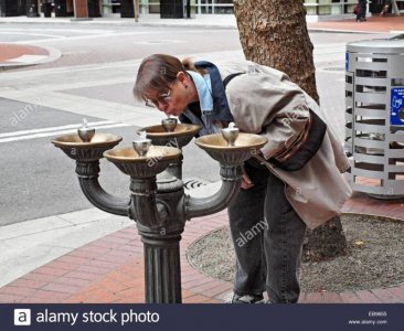 a-mature-woman-drinks-from-fountain-on-downtown-sidewalk-in-portland-EB9655.jpg
